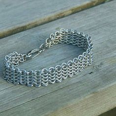 a silver chain bracelet sitting on top of a wooden bench