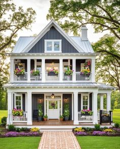 a white house with black shutters and flowers on the porch