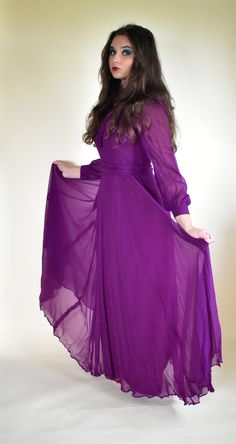 "Stunning statement dress in purple silk by Elka couture sized as a 38\" .  Perfect for an alternative wedding dress or simply to standout at an event. Team with high black heels for WOW factor. The acetate lining is cut quite narrow but the over chiffon is generous giving a swirl to the skirt when moved.  The dress has a Sweetheart bodice lining overlaid with chiffon that fits high on the neck. Sheer long sleeves complete the look of this Vampire bride dress. Note it comes with two separate len Purple Fitted Long Sleeve Gown, Fitted Long Sleeve Purple Gown, Flowy Full-length Party Dress, Purple Maxi Dress For Party, Purple Maxi Dress For Prom Season, Purple Maxi Dress For Prom, Flowy Full-length Maxi Dress For Party, Spring Maxi Dress For Costume Party, Purple Long Sleeve Maxi Dress For Wedding