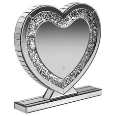 a silver heart shaped mirror on top of a metal stand with a diamond border around it