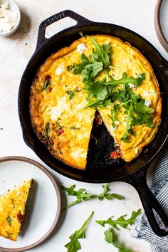 an omelet with greens and cheese in a cast iron skillet on a white table