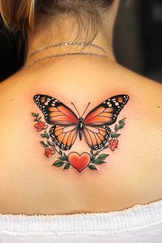 a woman's back shoulder with a butterfly and heart tattoo on her left side