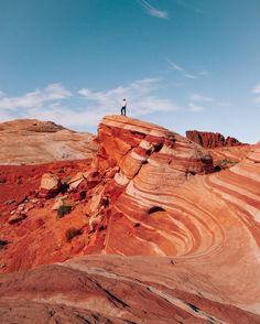 a man standing on top of a red rock formation