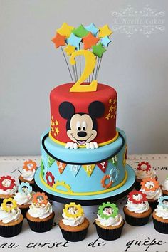 a mickey mouse birthday cake surrounded by cupcakes