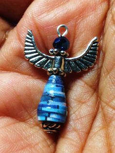 a person is holding a blue pendant with an egyptian bird on it's back