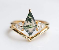 a gold ring with a green and white stone in the center, surrounded by diamonds