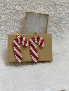 a pair of red and white beaded candy canes earrings in a gift box