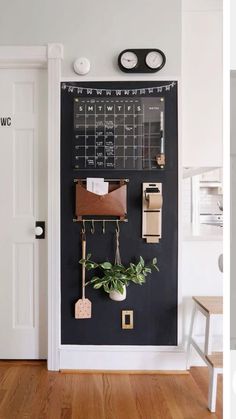 a chalkboard with magnets and plants on it in front of a white door