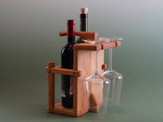 three wine glasses and two bottles in a wooden holder