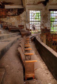 an abandoned building with benches and windows in the center, all lined up against one wall