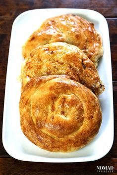 some food is on a white plate on a wooden table and it looks like cinnamon rolls