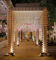 an outdoor wedding venue decorated in white and pink flowers with candles on the floor, surrounded by greenery