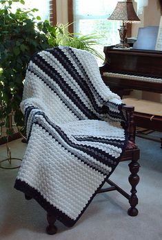 a crocheted blanket sitting on top of a chair next to a piano