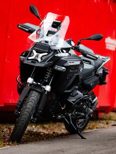 a black motorcycle parked next to a red wall