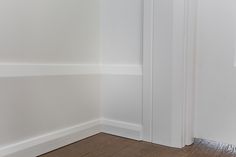 the corner of a room with white walls and wood flooring is painted in an off - white color