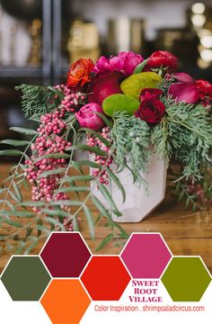 a vase filled with lots of flowers on top of a wooden table next to greenery