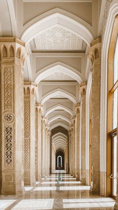 the hallway is lined with arches and columns, leading to two large windows on each side