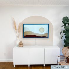 a painting is hanging on the wall above a white cabinet