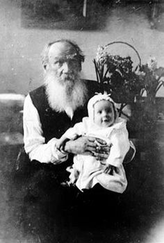 an old black and white photo of a man with a beard holding a baby in his lap