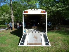 an old school bus is parked in the grass with its doors open and people standing around