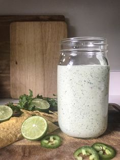 a glass jar filled with food sitting on top of a wooden table next to sliced limes