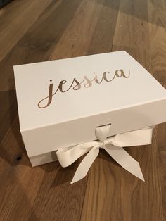 a white box with the word jesus on it sitting on a wooden floor next to a pair of scissors