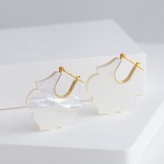 Description Talkative's signature Crest earrings made with 18k yellow gold and white mother of pearl. Each mother of pearl is elegant and unique in its own way, perfect for any season. The lotus shape is pure and elegant just like a beautiful lotus blossoming on the water. These earrings are just the right size to draw attention without stealing the show. The Crest series is inspired by traditional emblems from different cultures around the world. The various shapes of the emblems are simplified Different Cultures Around The World, Lotus Shape, Lotus Earrings, Lotus Blossom, The Lotus, Japanese Traditional, Mother Of Pearl, To Draw, Lotus