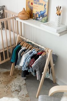 a baby's clothes rack in front of a crib and bookshelf