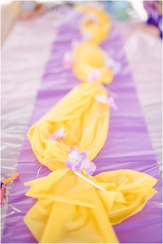 purple and yellow table runners with flowers on them for a party or wedding reception at the beach