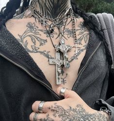 a woman with tattoos and piercings on her chest holding onto a cross pendant necklace