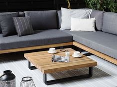 a living room with grey couches and coffee table on the floor next to potted plants