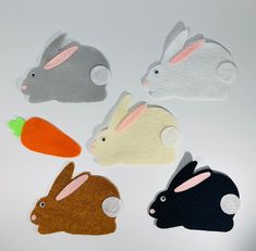 four felt rabbits and carrots on a white surface