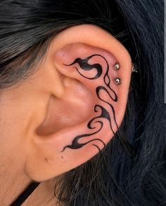 a close up of a person's ear with some tattoos on their left side