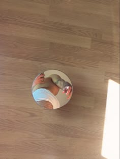 a person's reflection in a mirror on a wooden floor with light coming through the window