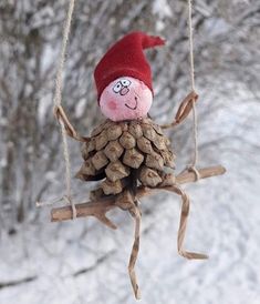 a pine cone ornament hanging from a tree branch with a red hat on it