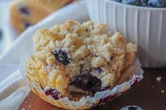 a muffin with blueberries in it sitting on a table next to a bowl of berries