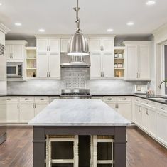 a large kitchen with white cabinets and an island