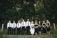 a group of people standing next to each other in front of some trees and grass