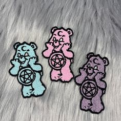 three teddy bears sitting on top of a fur covered floor next to each other and one is wearing a pentagram