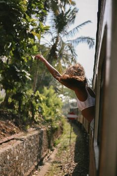 a woman leaning out the side of a train window