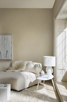 a white couch sitting on top of a wooden floor next to a table and lamp