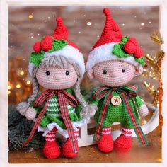 two crocheted dolls sitting next to each other in front of a christmas tree