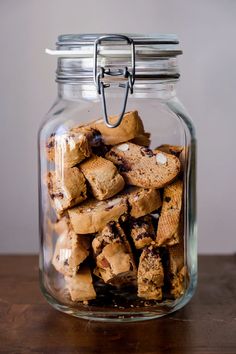 a glass jar filled with cookies on top of a wooden table