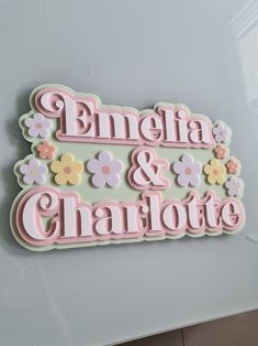 a sign that says emelia and charlotte on the side of a wall with flowers