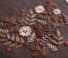 a close up of a piece of embroidered fabric with flowers and leaves on the side