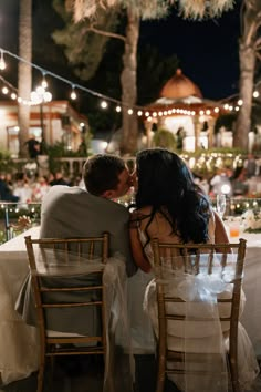 a bride and groom sitting at a dinner table