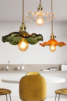 three lights hanging from the ceiling above a dining room table with chairs and stools