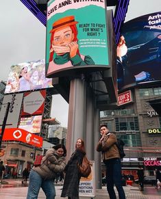 three people standing next to a street sign with an advertisement on it's side