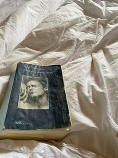 a book sitting on top of a bed covered in white sheets