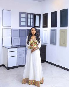 a woman in a white dress standing in front of some cabinets and cupboards on the wall